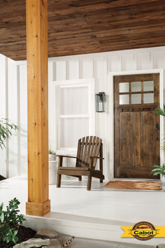 a wooden chair sitting on top of a porch next to a door and potted plants