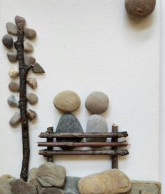 two people are sitting on a bench made out of rocks and wood with a tree in the background