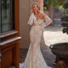 a woman in a white wedding dress standing on a brick walkway with her hands on her hips