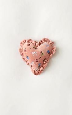 a pink heart shaped pillow sitting on top of a white surface