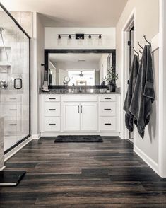 a bathroom with white cabinets and dark wood flooring is shown in black and white