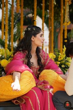 a woman sitting on top of a bench wearing a pink and yellow dress with gold accents