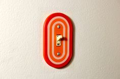 an orange and white light switch plate on a wall with a single outlet in the middle