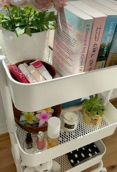 a white shelf filled with lots of books and other items next to a potted plant