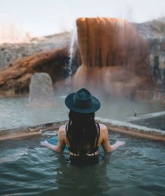 a woman wearing a hat sitting in a hot tub with water coming out of it