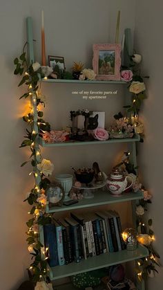 a shelf filled with lots of books covered in flowers and candles next to a wall