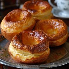 some very tasty looking pastries sitting on a glass plate with a cup in the background