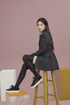 a woman sitting on top of a stool wearing black and white striped dress with high heels