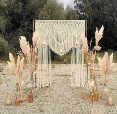 some vases with flowers and plants in them on the ground near a white curtain