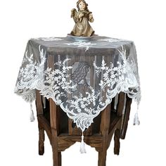 an angel figurine sitting on top of a table covered with a white lace