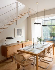 the dining table is set for six with place settings on each side and under the stairs