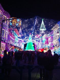 people are standing in the middle of a street covered with christmas lights