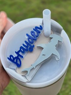 a person holding a plastic cup with a shark on it and the word below it