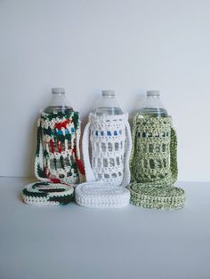 three crocheted water bottles sitting next to each other on a white counter top