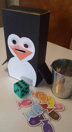 a penguin and some dices on a table with a box in the shape of a cube