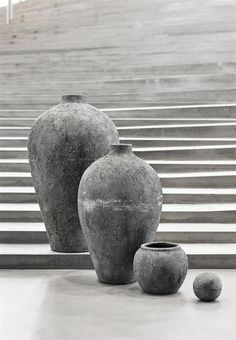 three vases sitting on the ground in front of some steps