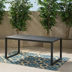 a black table sitting on top of a blue rug next to a tree filled wall