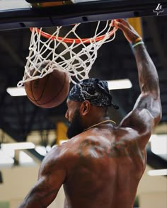 a shirtless man dunking a basketball into the hoop