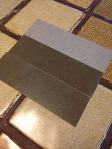 a square piece of metal sitting on top of a tiled floor with light coming through it