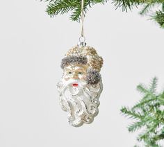 a glass ornament hanging from a christmas tree with a santa clause head on it