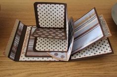 four folded notebooks sitting on top of a wooden table next to a coffee cup