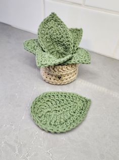 a crocheted basket with a green leaf on top and two smaller baskets in the middle