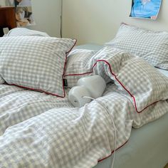 an unmade bed with two pillows on it and a stuffed animal in the middle