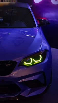 the front end of a blue bmw sports car with its eyes glowing in neon lights