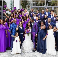 a large group of people in purple and blue outfits posing for a photo together outside