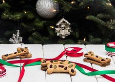 some dog treats are laying on a table next to a christmas tree with red and green ribbons