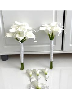 three white flowers in vases sitting on a counter