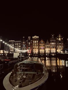 a boat is parked in the water near some buildings at night with lights on it