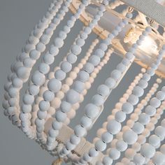 a white chandelier with beads hanging from it's sides and a light fixture in the background