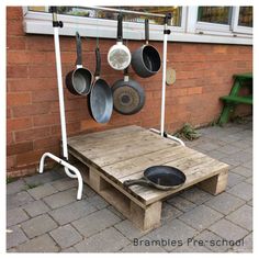 an outdoor table with pots and pans hanging from it's hooks on the wall