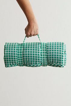 a person's hand holding a green and white checkered duffel bag in the air