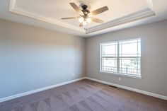 an empty room with a ceiling fan and carpeted floor in front of the window