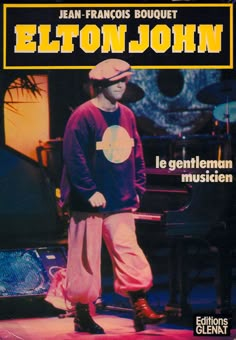 a man standing on top of a stage in front of a piano and keyboard with the caption elton john