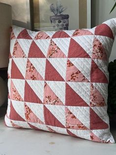 a red and white quilted pillow sitting on top of a table next to a lamp