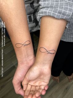 two people holding hands with tattoos on their arms and the words love are written in cursive writing