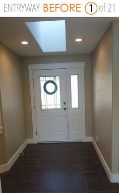 an empty entryway with a wreath on the door and tile floor in front of it