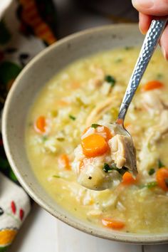 a person holding a spoon full of chicken and rice soup