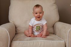 a baby sitting in a chair smiling at the camera