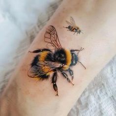 a bum tattoo on the leg of a person with two bees in front of it