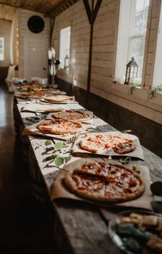 several pizzas are lined up on the long table