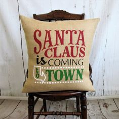 a pillow that says santa claus is coming to town on the back of a chair