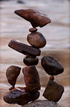 a stack of rocks sitting on top of each other in the sand next to water