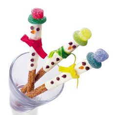 four toothbrushes decorated like snowmen in a cup with candy on the top