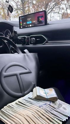 the inside of a car with money and cell phone on it's dash board