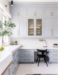 a kitchen with gray cabinets and white counter tops, along with a black chair in the center