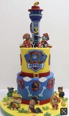 a three tiered cake with toy figures on the top and bottom layer is decorated in yellow, blue, and red